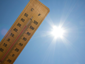 Praca w upale - termometr z ukazaną wysoką temperaturą, w tle ostre słońce