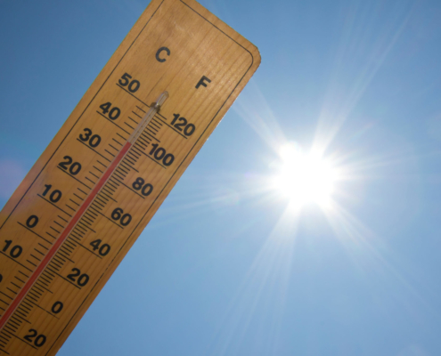 Praca w upale - termometr z ukazaną wysoką temperaturą, w tle ostre słońce