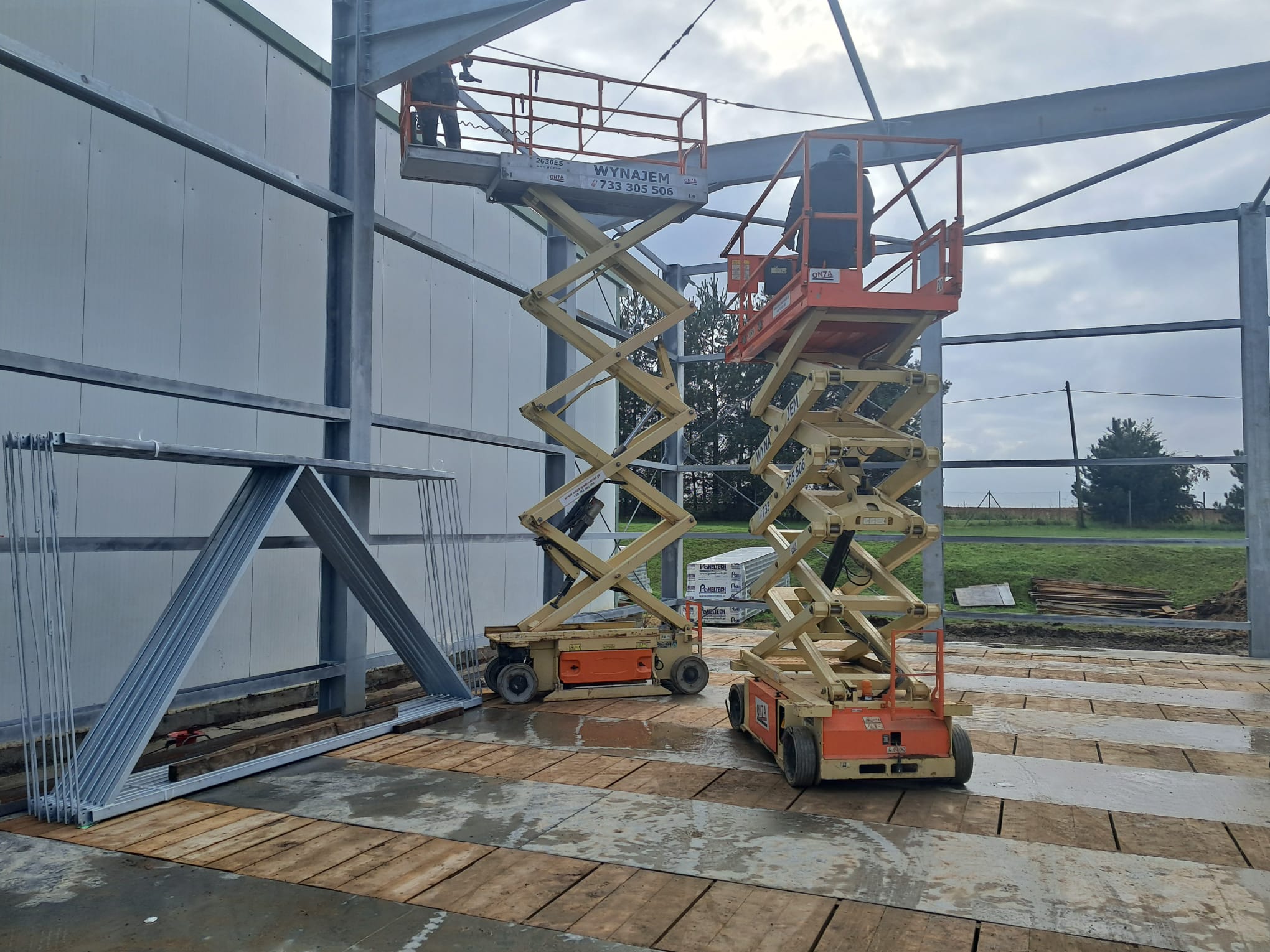 wynajem podnośników oława Podnośniki przy pracy na placu budowlanym