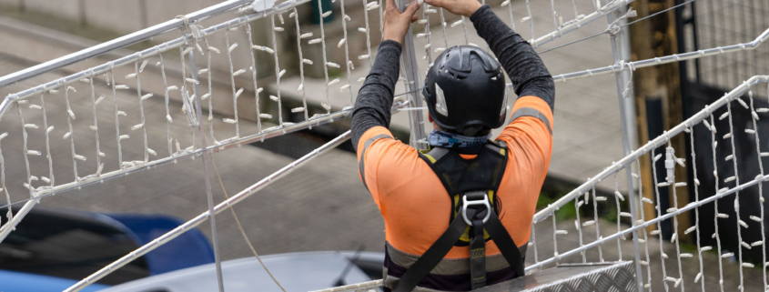 Mężczyzna zawieszający świetlną dekorację świąteczną