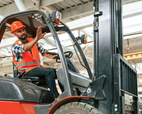 Mężczyzna na wózku widłowym machający do współpracowników